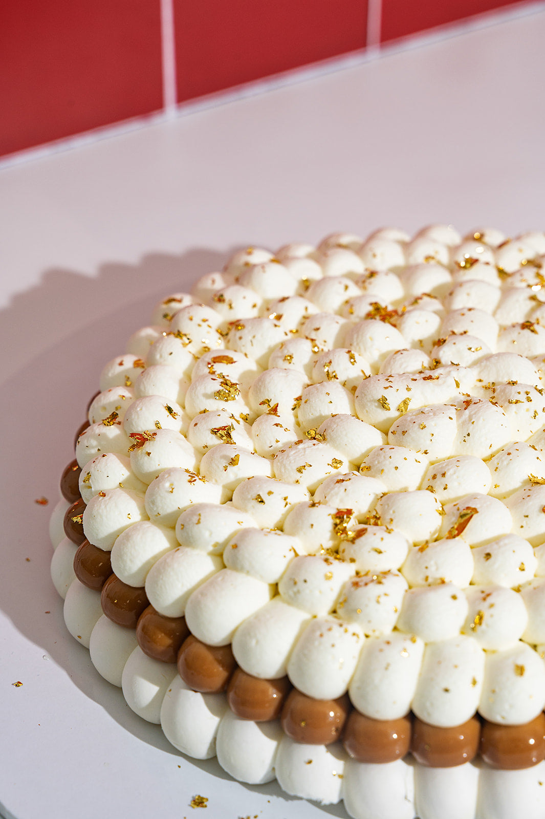 Close-up of Banana Pavlova showing whipped cream, dulce de leche layer and golden flakes on gluten free meringue