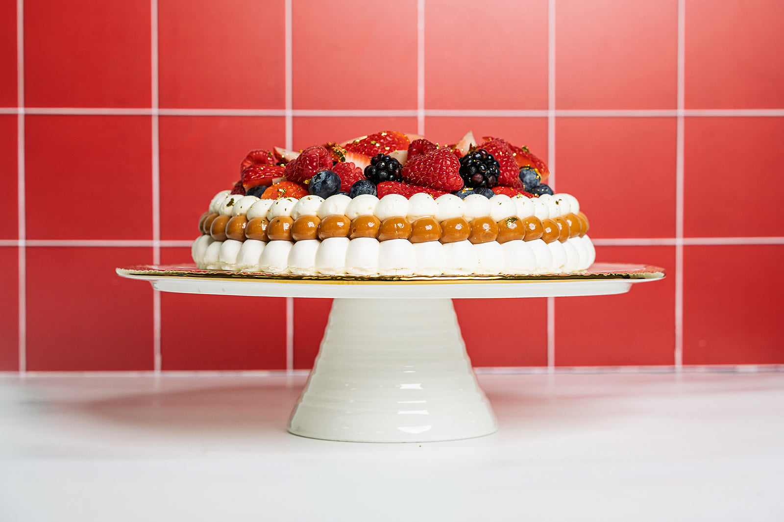 Side view of mixed berries pavlova showing layers of meringue, dulce de leche and whipped cream, handcrafted by The Golden Pavlova in Miami.