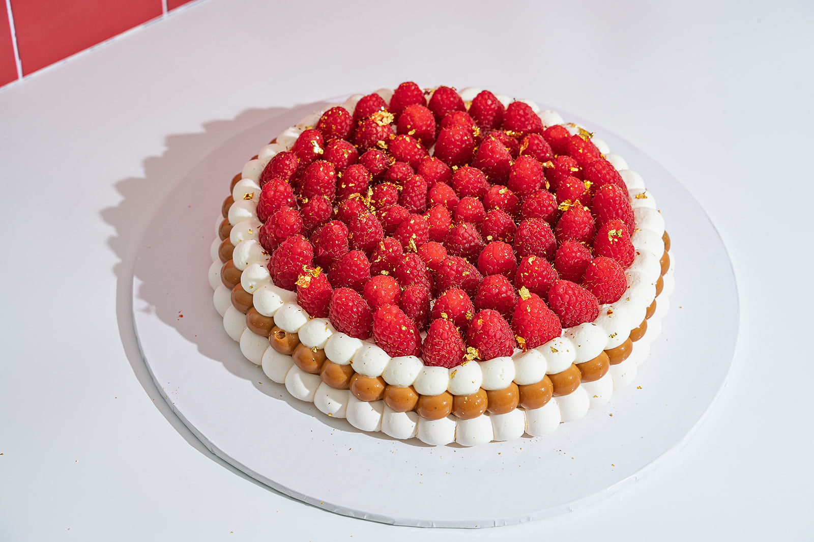 Raspberry pavlova cake with fresh raspberries, whipped cream and golden flakes by The Golden Pavlova in Miami, Florida